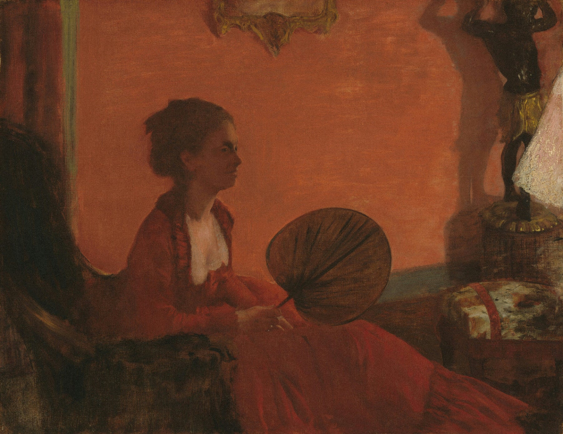 Woman in a red dress holding a fan in a warm-toned room with a statue in the background